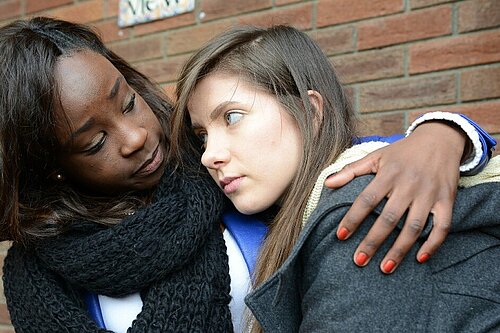 A woman gives a girl a hug